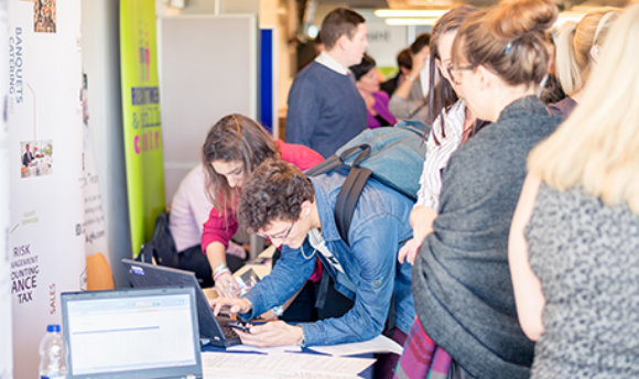 Students using a laptop at a busy recruitment fair, Ӱֱcampus, Edinburgh