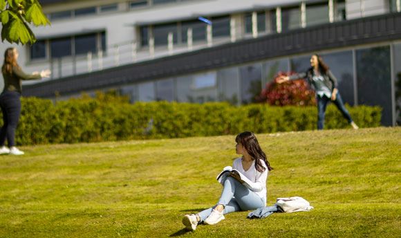 Students playing frisbee on the grass outside Ӱֱ, Edinburgh