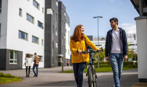 A Ӱֱstudent with a bike talking to a fellow student on campus, Edinburgh