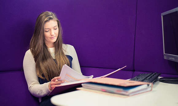 A Ӱֱ student reading over their work against a purple wall