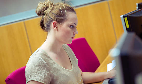 A Ӱֱ student working alone at their computer desk, Edinburgh