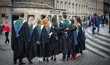A row of Ӱֱgraduands standing in a row wearing their gowns outside Usher Hall