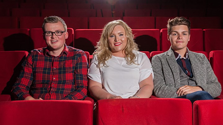 Three Ӱֱ students sitting in plush red seats at the theatre