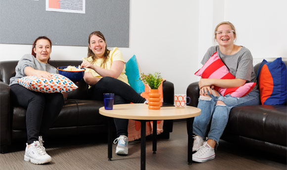 Three female students enjoy popcorn while watching a film in their ӰֱStudent Accommodation